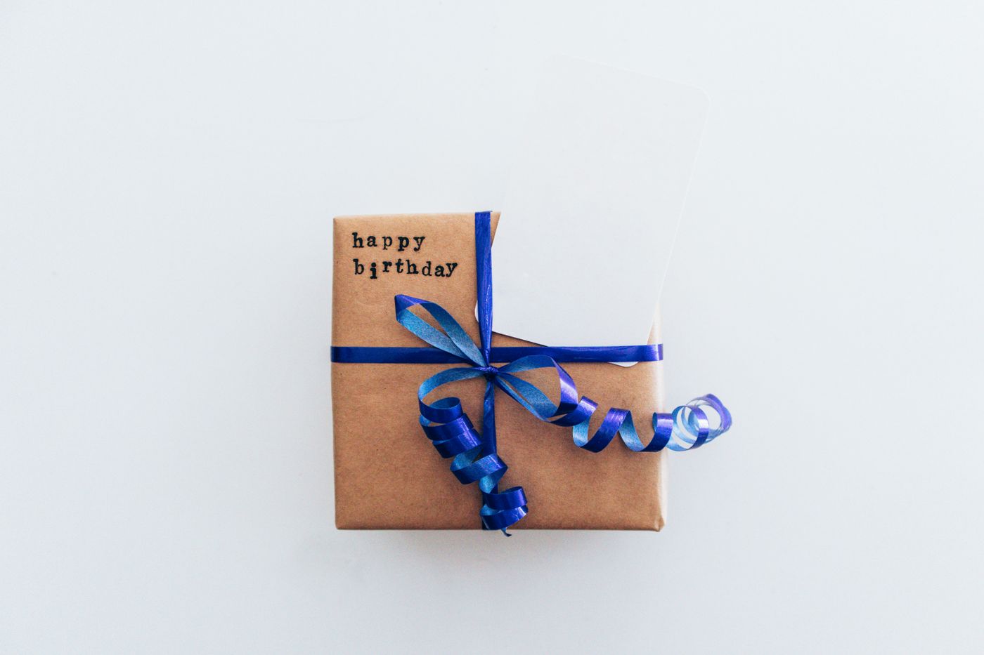 A kraft paper gift box tied with blue ribbon and a happy birthday tag
